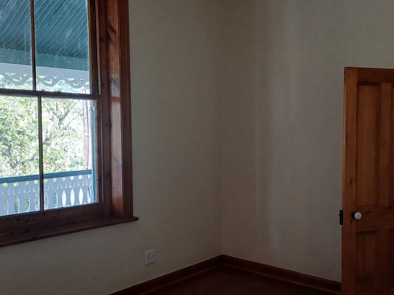 A bright, empty office space featuring classic timber window frames, matching timber doors, and traditional architraves, offering a clean canvas for professional use.