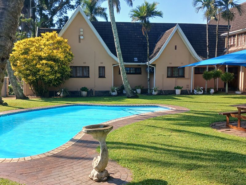 A well-maintained outdoor pool area featuring a swimming pool with brick paving, set against the rear elevation of the main dwelling.