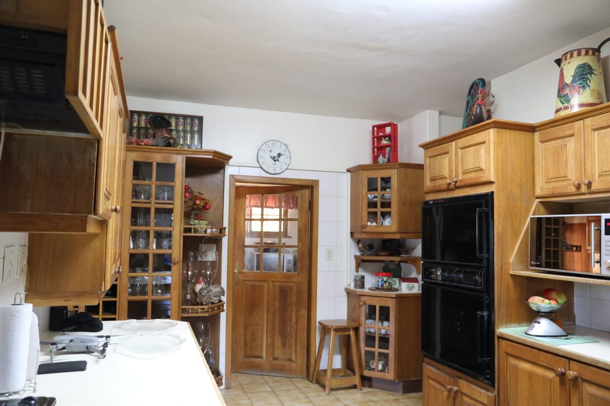 A traditional kitchen featuring extensive built-in wooden cabinetry, a double oven, tiled flooring, and a classic glass-paneled wooden door.