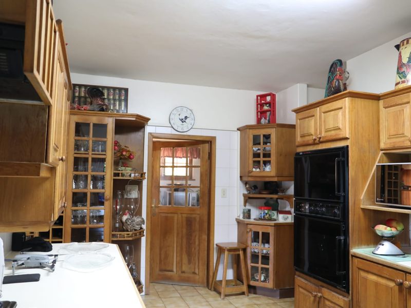 A traditional kitchen featuring extensive built-in wooden cabinetry, a double oven, tiled flooring, and a classic glass-paneled wooden door.