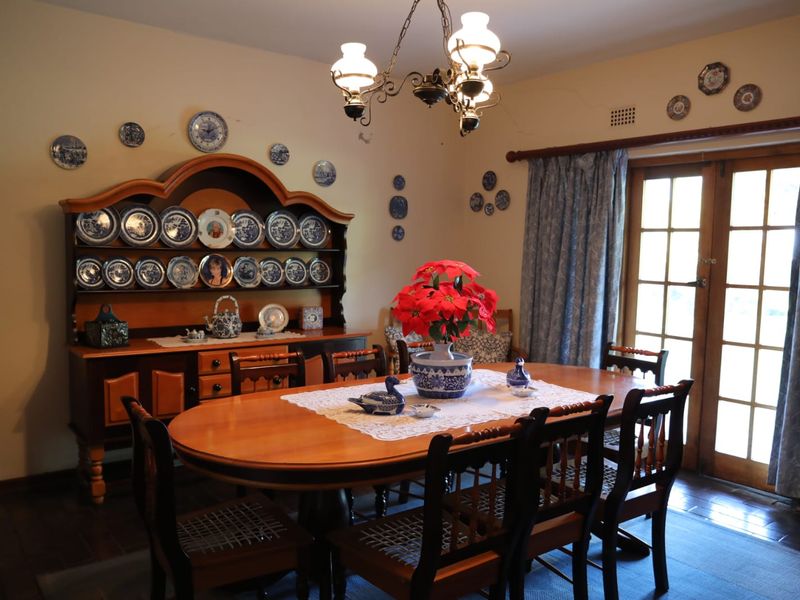 A traditional dining room featuring timber flooring, a classic chandelier, and direct access to the outdoors through timber-framed french doors.