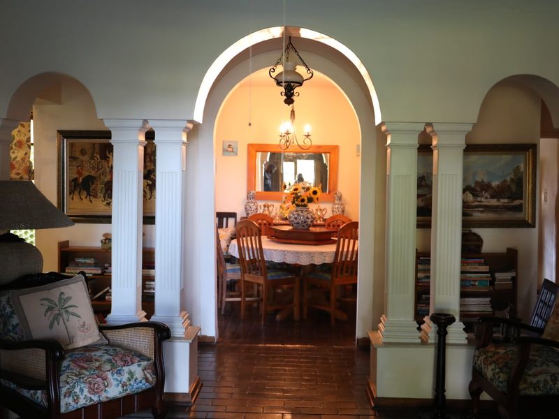 A formal dining area featuring an elegant arched entryway with decorative columns, hardwood flooring, and a classic chandelier.
