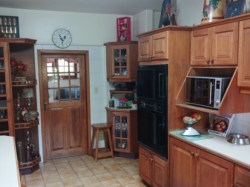 Traditional kitchen featuring extensive built-in wooden cabinetry, a double oven, built-in microwave, tiled backsplash, and durable tiled flooring.