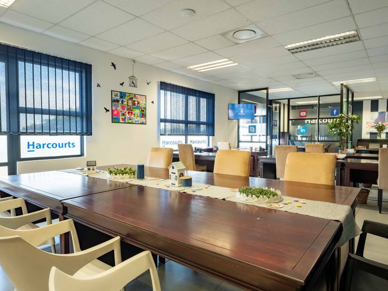 A professional open-plan office space featuring suspended ceilings, recessed lighting, large windows with vertical blinds, and modern glass partitioning for a bright, functional workspace.