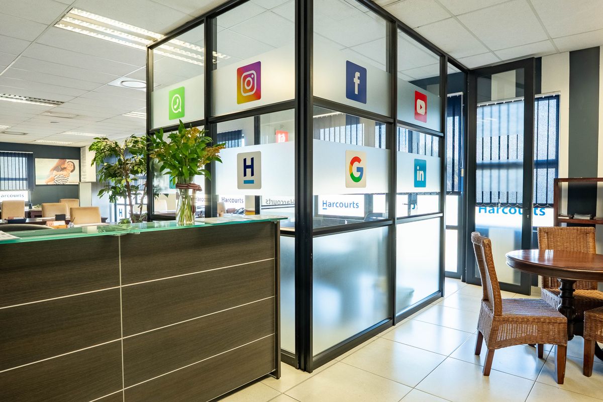 Professional office space featuring a modern reception desk, glass-partitioned meeting areas, suspended ceilings, and tiled flooring with integrated vertical blinds.