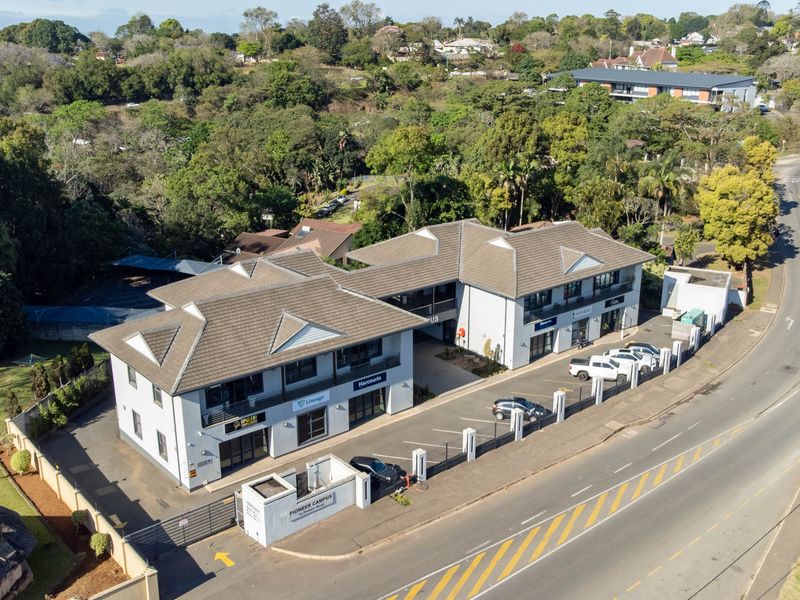 Aerial view of a multi-tenant office campus featuring a tiled roof structure, dedicated paved parking, and secure perimeter access.