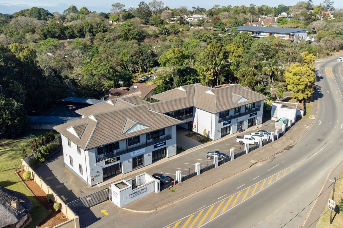 Aerial view of a multi-tenant office campus featuring a tiled roof structure, dedicated paved parking, and secure perimeter access.