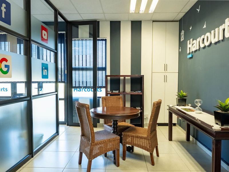 A professional office space featuring glass partitions, built-in storage cabinetry, tiled flooring, and modern accent wall detailing.