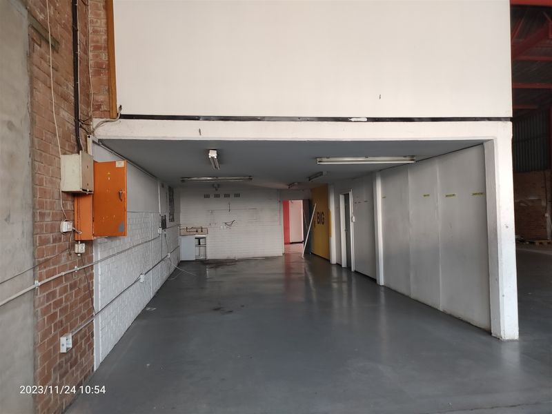 An industrial utility space featuring exposed brickwork, durable epoxy flooring, fluorescent lighting, and a basic built-in sink area.