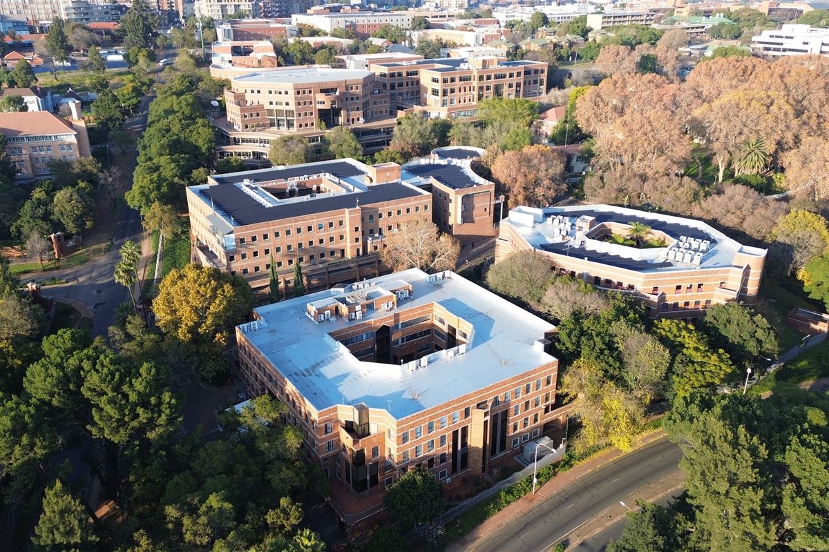 Aerial view of a multi-building office complex featuring brick facades, flat roofs with HVAC units, and surrounding landscaped grounds.