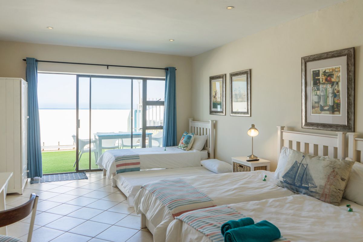 Spacious bedroom featuring tiled flooring, recessed ceiling lighting, and large sliding glass doors providing direct access to a private patio with ocean views.