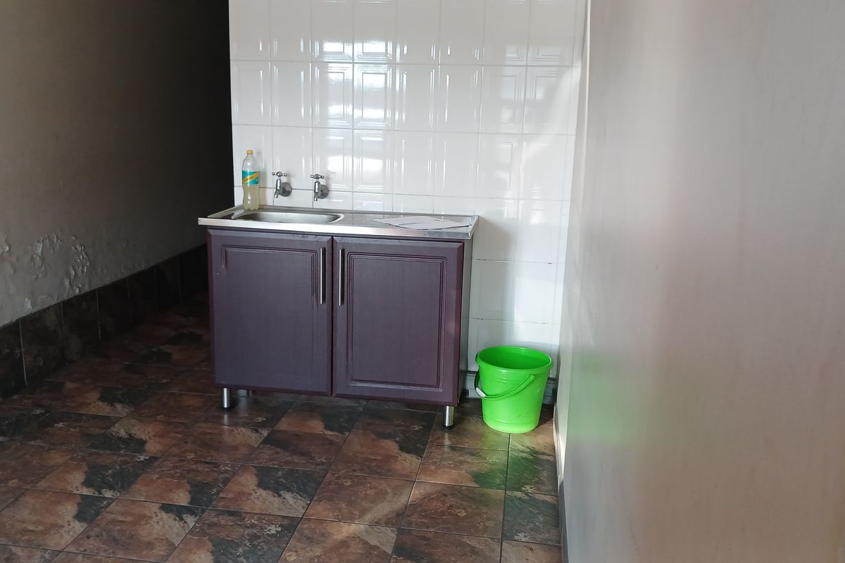 A functional utility space featuring a stainless steel sink, built-in cabinetry, and tiled splashback, requiring minor cosmetic attention to the wall finishes.
