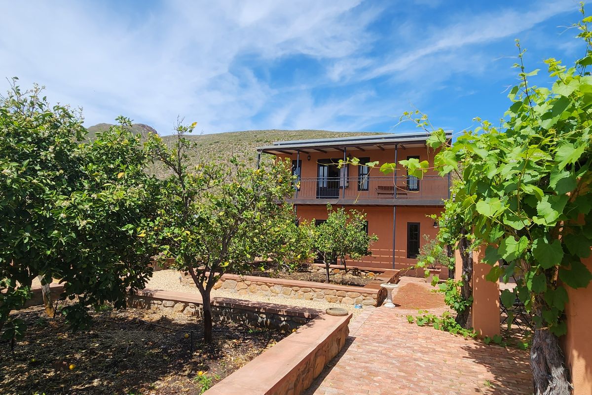 A view of the rear exterior featuring a two-story terracotta building, stone retaining walls, and a brick-paved garden path.