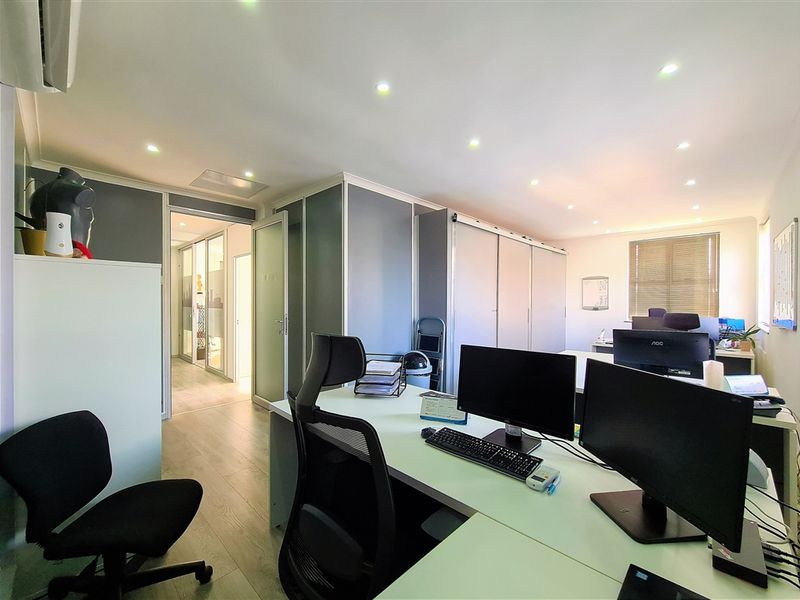 A well-maintained office space featuring modern partition walls, recessed downlighting, and laminate flooring, providing a professional and functional work environment.