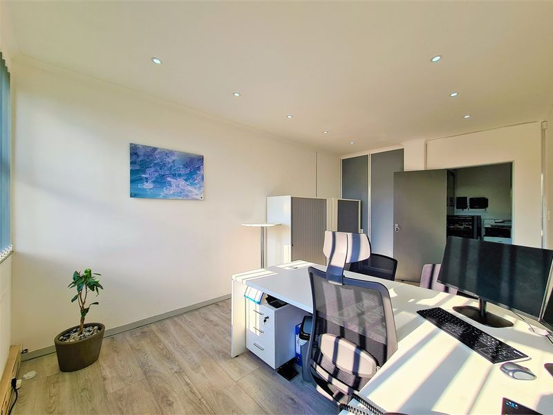 A well-lit, modern office space featuring laminate flooring, recessed ceiling lighting, and integrated storage cupboards, providing a clean and professional work environment.