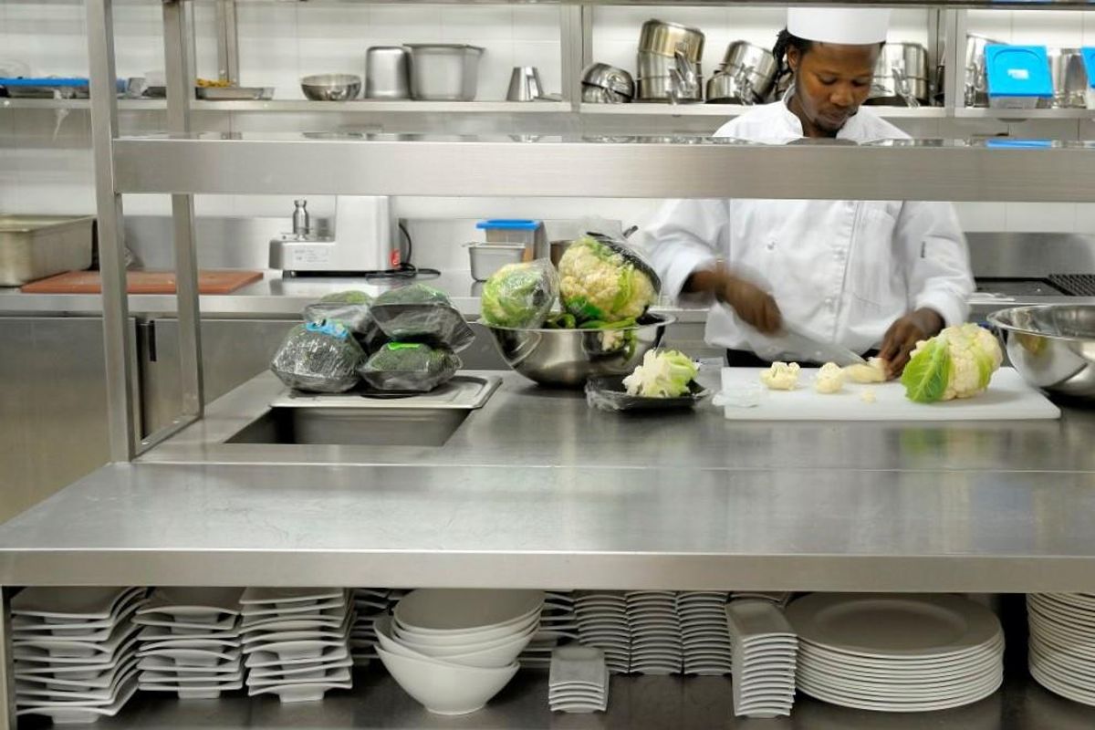 A professional commercial kitchen workspace featuring stainless steel countertops, integrated shelving, and organized storage for culinary equipment and food preparation.