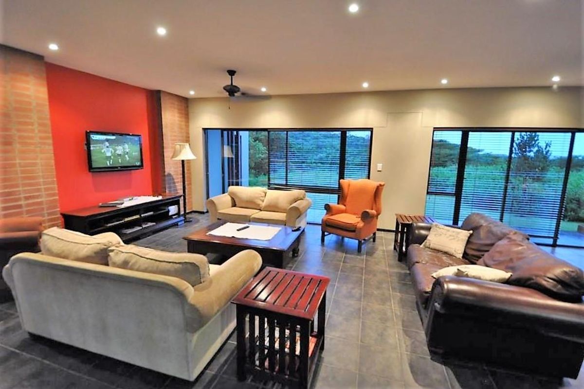 Spacious living area featuring large sliding glass doors, recessed ceiling lighting, and a distinctive red brick accent wall.