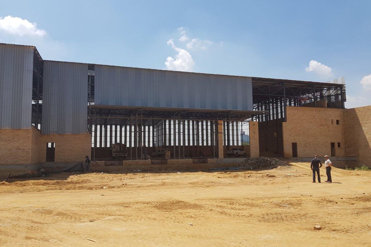 Exterior view of an industrial property under construction, featuring a steel frame structure and brick masonry walls.