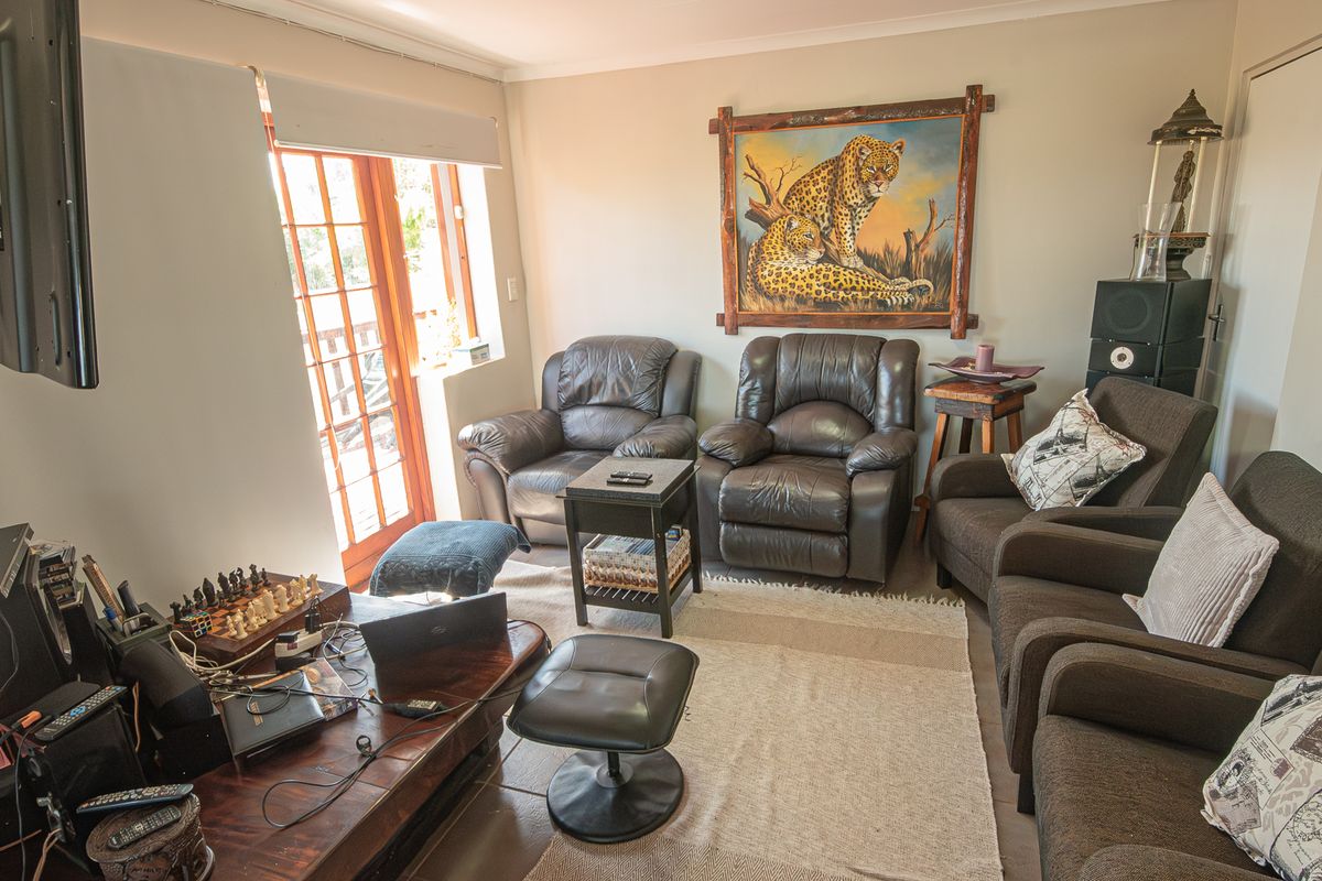 A cozy living room featuring tiled flooring, a wall-mounted television, and glass-paneled double doors providing access to the exterior.