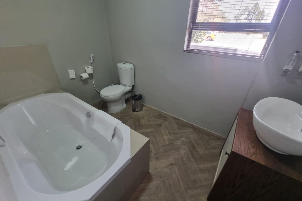 A functional bathroom featuring a built-in bathtub, a modern vessel sink on a vanity cabinet, and a toilet with a bidet spray.