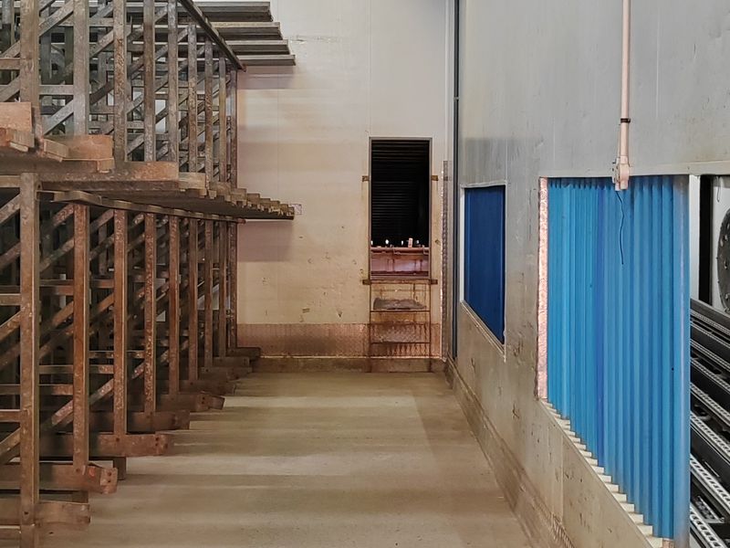 Industrial utility space featuring concrete flooring, insulated wall panels, and fixed metal shelving units suitable for storage or processing operations.