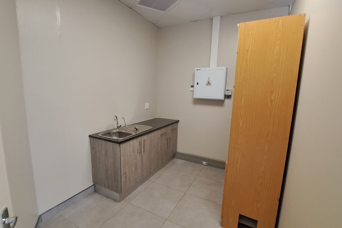 A functional utility space featuring a stainless steel sink, laminate cabinetry, and an accessible electrical distribution board.