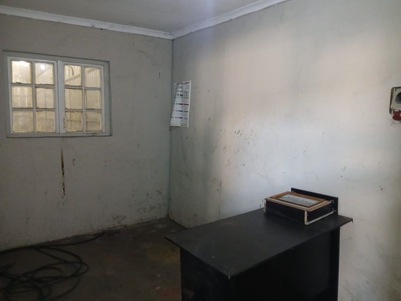 A basic industrial utility space featuring concrete flooring and a multi-pane window, suitable for storage or workshop use.