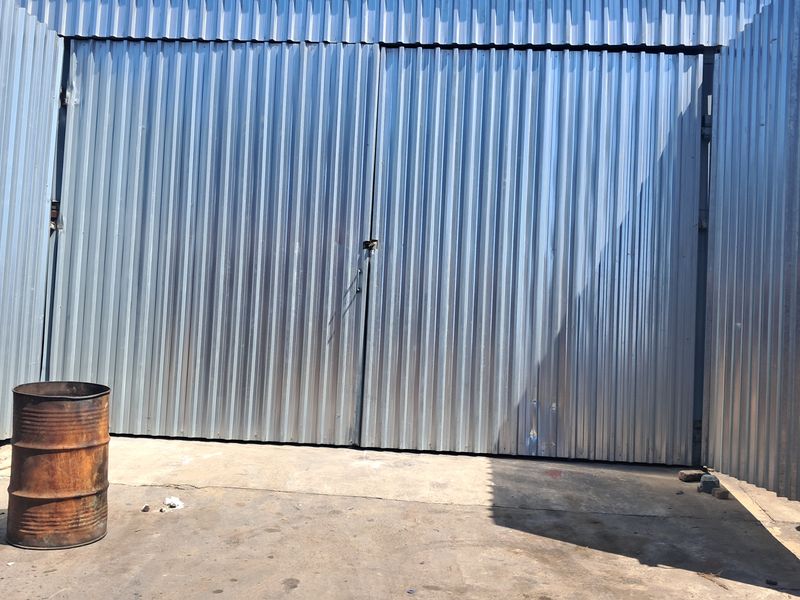 Industrial exterior area featuring large corrugated metal sliding doors and a concrete hardstand, suitable for loading or storage access.