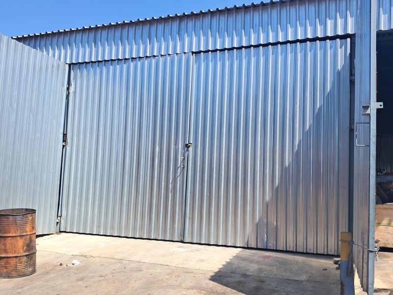 Industrial warehouse exterior featuring large corrugated metal sliding doors and a concrete apron entrance.