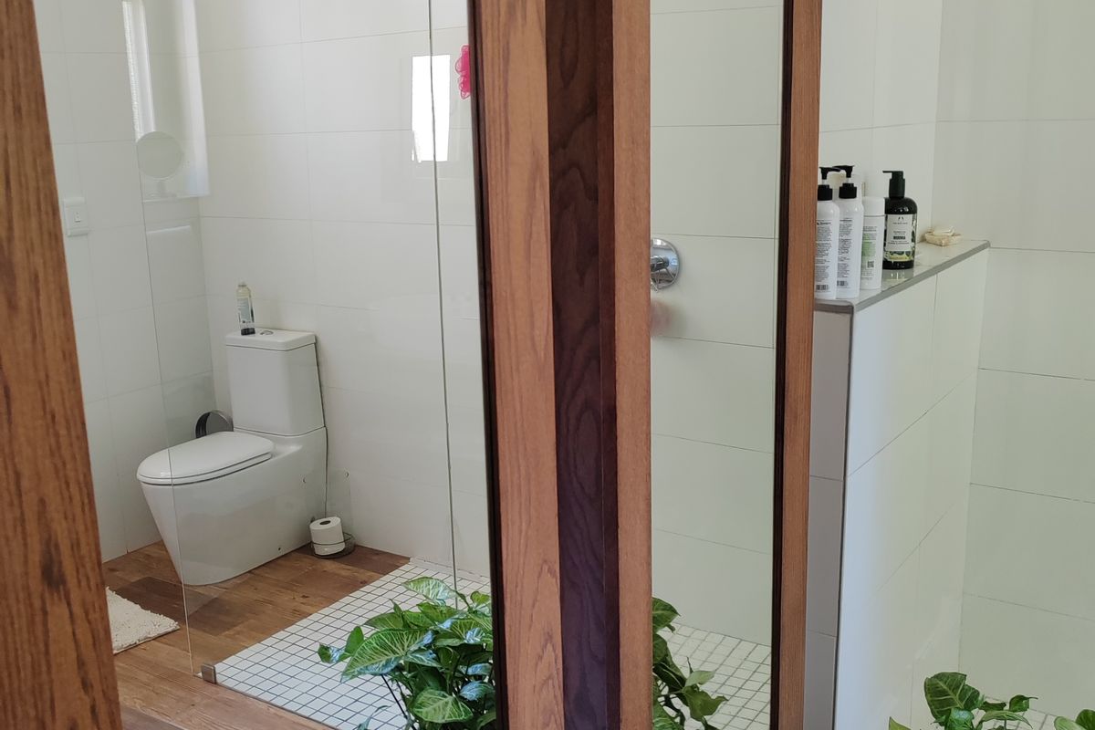 A modern bathroom featuring a glass-enclosed shower, wall-mounted shower head, built-in tiled ledge, and contemporary floor tiling.