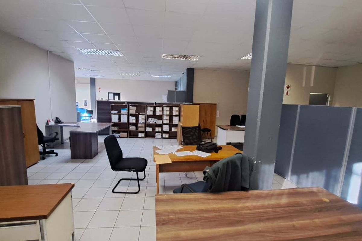 Open-plan office space featuring suspended ceilings, recessed lighting, and ceramic tiled flooring with integrated structural columns and partitioning.