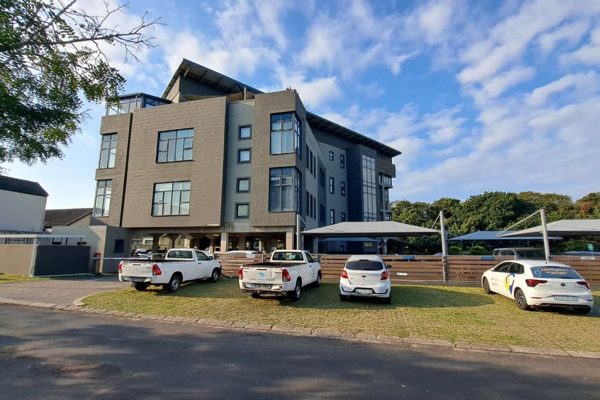 A modern multi-story office building featuring contemporary facade cladding, dedicated covered parking bays, and well-maintained landscaped grounds.