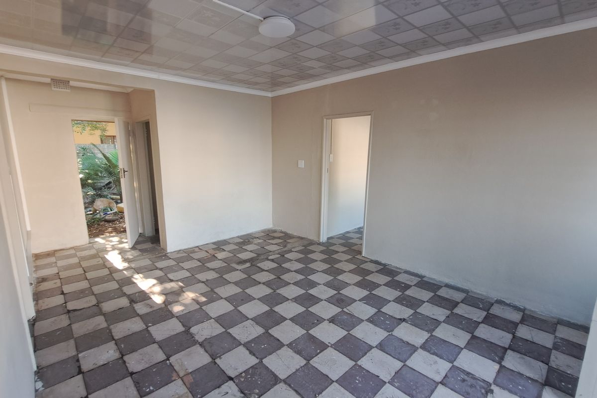 An empty living area featuring checkered floor tiles and a drop ceiling, providing a blank canvas for renovation or restyling.