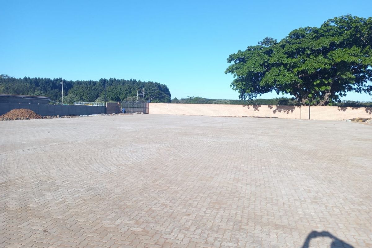 A spacious, paved industrial yard featuring a secure perimeter wall and metal gate access, suitable for storage or logistics operations.