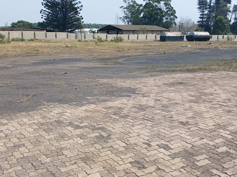 Expansive industrial yard featuring paved surfaces, perimeter walling, and large storage tanks, suitable for heavy vehicle access or outdoor storage.