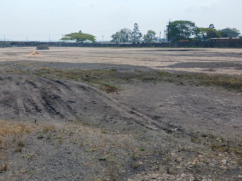 A large, cleared industrial plot of land featuring a perimeter wall and expansive open space suitable for development.
