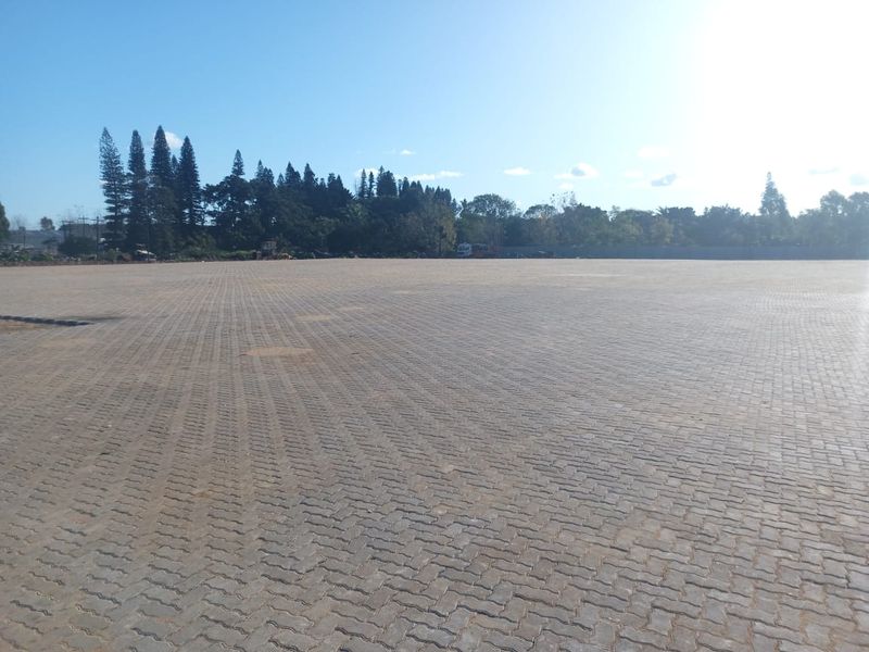 A large, open industrial yard featuring extensive interlocking paved surfacing, suitable for heavy-duty storage or logistics operations.