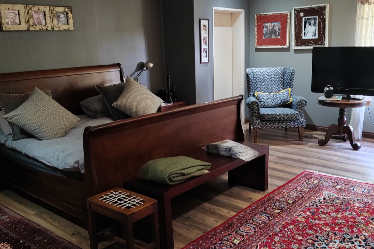 Spacious bedroom featuring laminate flooring, neutral grey walls, and recessed downlighting, offering a comfortable and well-maintained living space.
