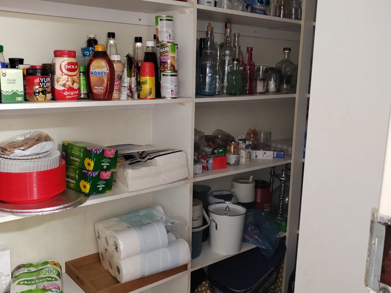 A functional walk-in pantry or scullery area featuring extensive built-in shelving for storage and organization.