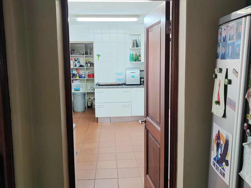A functional scullery area featuring tiled flooring, built-in cabinetry, and stone countertops, providing additional prep and storage space adjacent to the main kitchen.