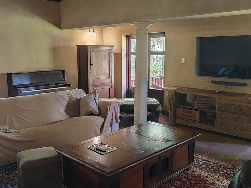 A cozy living room featuring exposed timber ceiling beams, a structural column, and tiled flooring, with direct access to an outdoor area through french doors.