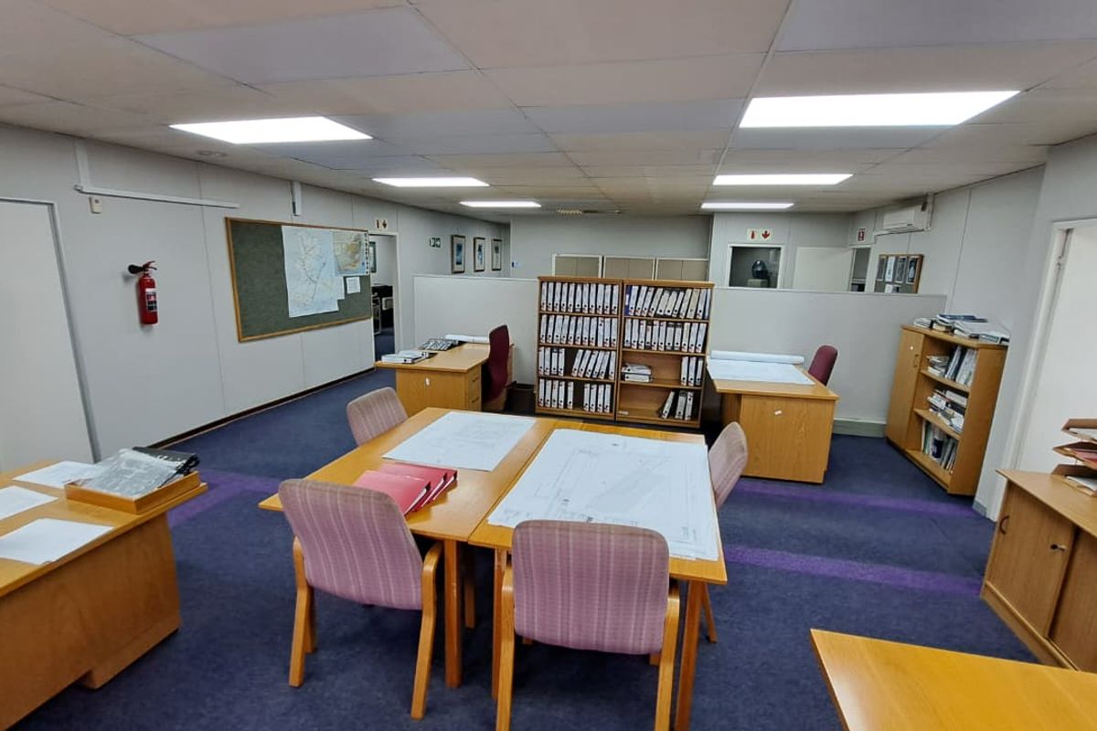A functional open-plan office space featuring a suspended ceiling, recessed lighting, and integrated air conditioning, suitable for a collaborative work environment.