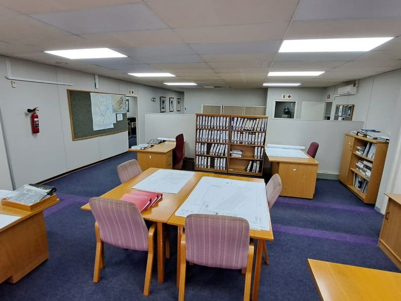 A functional open-plan office space featuring a suspended ceiling, recessed lighting, and integrated air conditioning, suitable for a collaborative work environment.