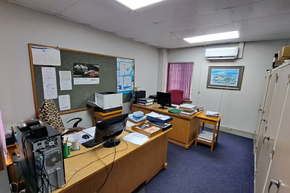 A functional office space featuring a drop ceiling, integrated air conditioning, and built-in storage cabinets with carpeted flooring.