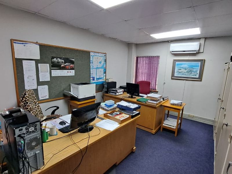 A functional office space featuring a drop ceiling, integrated air conditioning, and built-in storage cabinets with carpeted flooring.