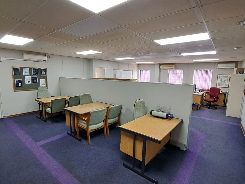Open-plan office space featuring a partition wall, suspended ceiling with recessed lighting, split-system air conditioning units, and carpeted flooring.
