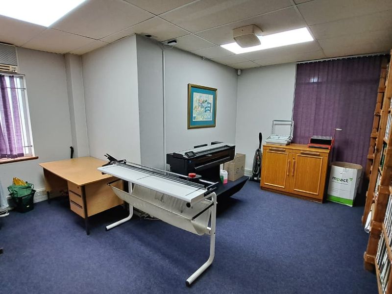 A functional office space featuring a suspended ceiling, recessed lighting, built-in shelving units, and an integrated air conditioning system.