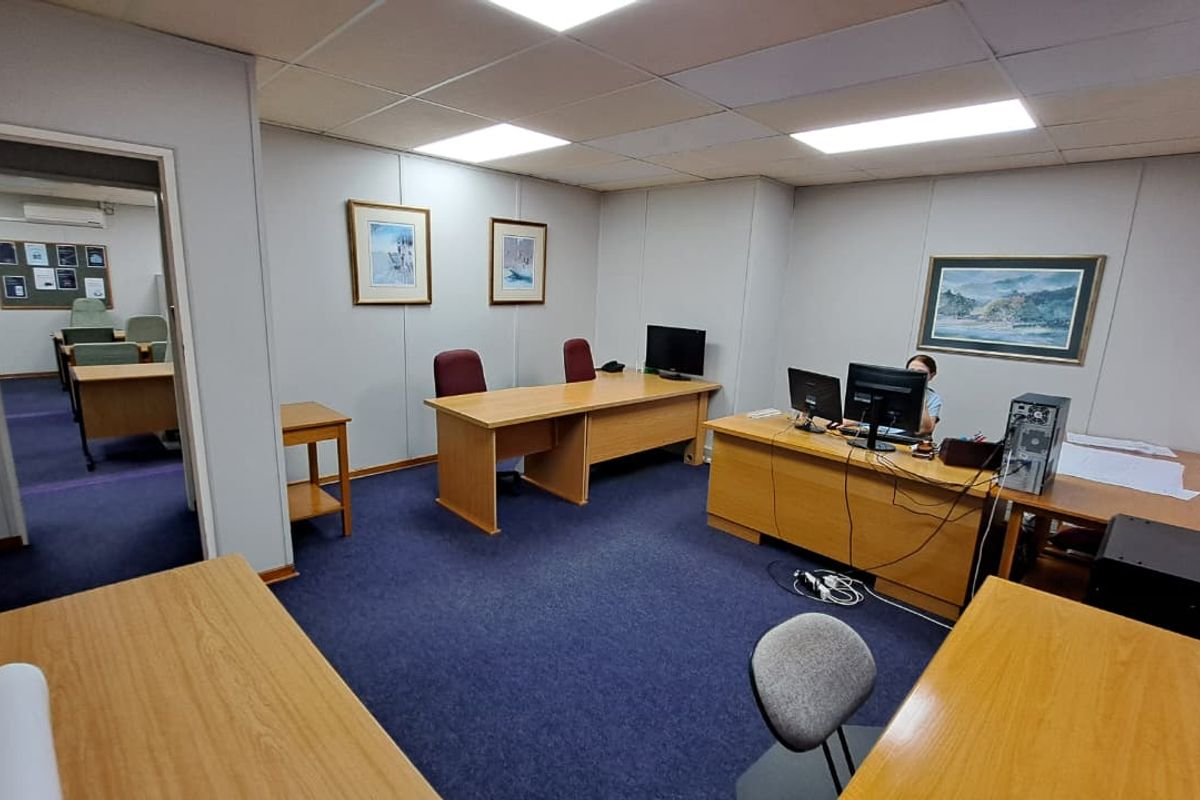 A functional office space featuring a suspended ceiling with recessed lighting and blue carpeting, providing a professional work environment.