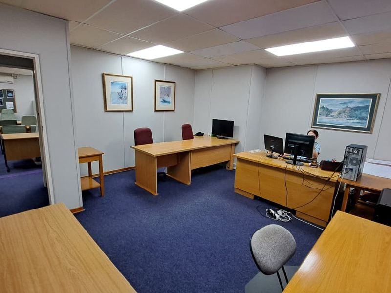 A functional office space featuring a suspended ceiling with recessed lighting and blue carpeting, providing a professional work environment.