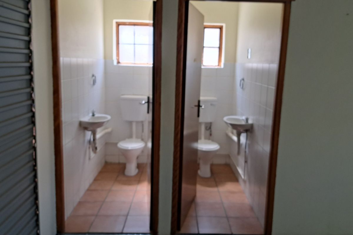 Two separate, functional office restrooms featuring tiled flooring, wall-mounted basins, and close-coupled toilets.